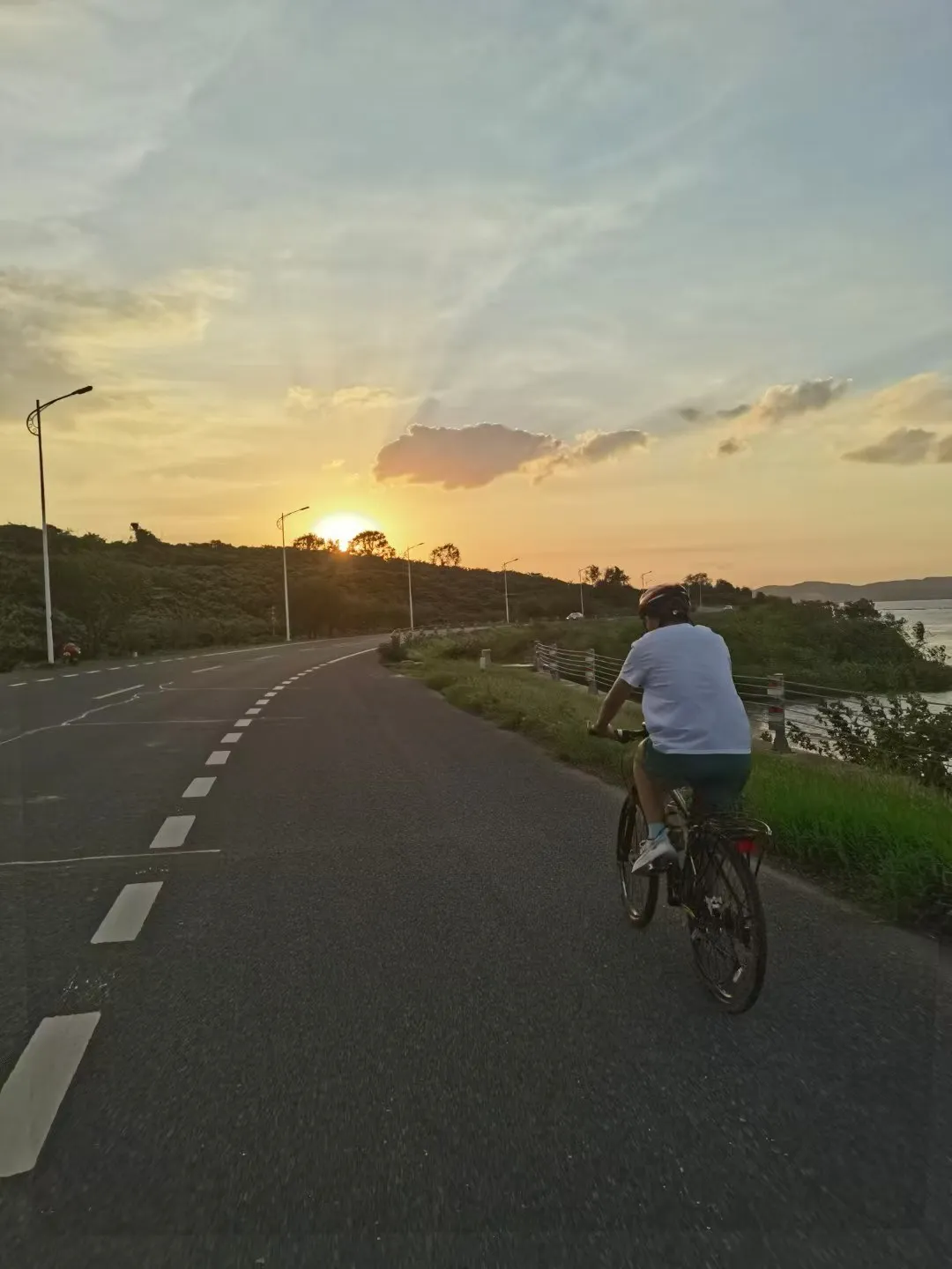 Zimo cycling along a coastal road at sunset