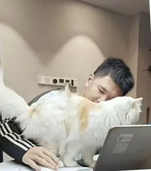 Zimo studying with Fantuan the cat on the desk